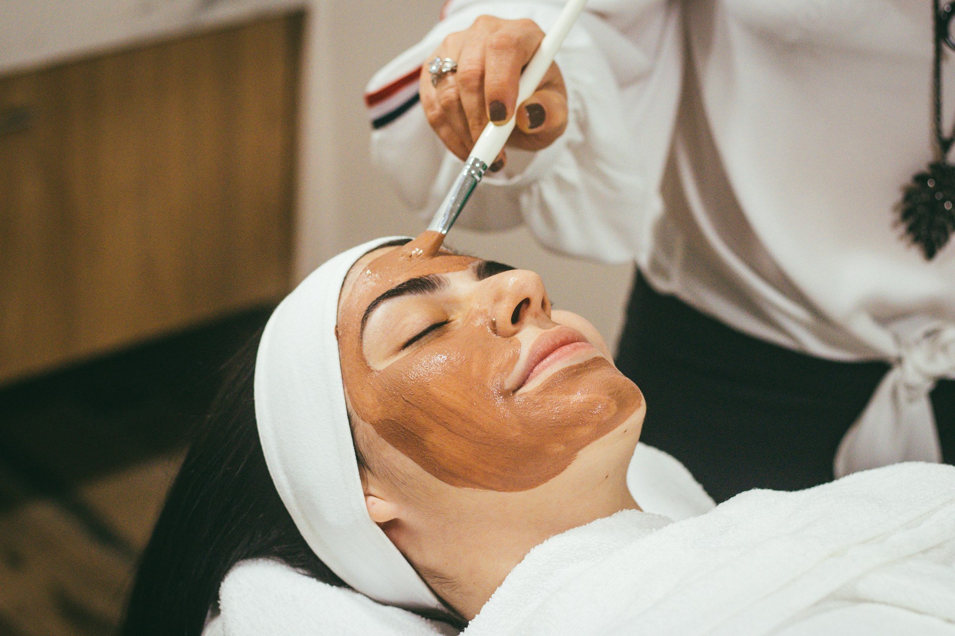 woman on an inclined chair receiving facial treatment in a spa
